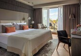 A hotel room with a large bed, a desk, a chair, and a view of the outdoors.