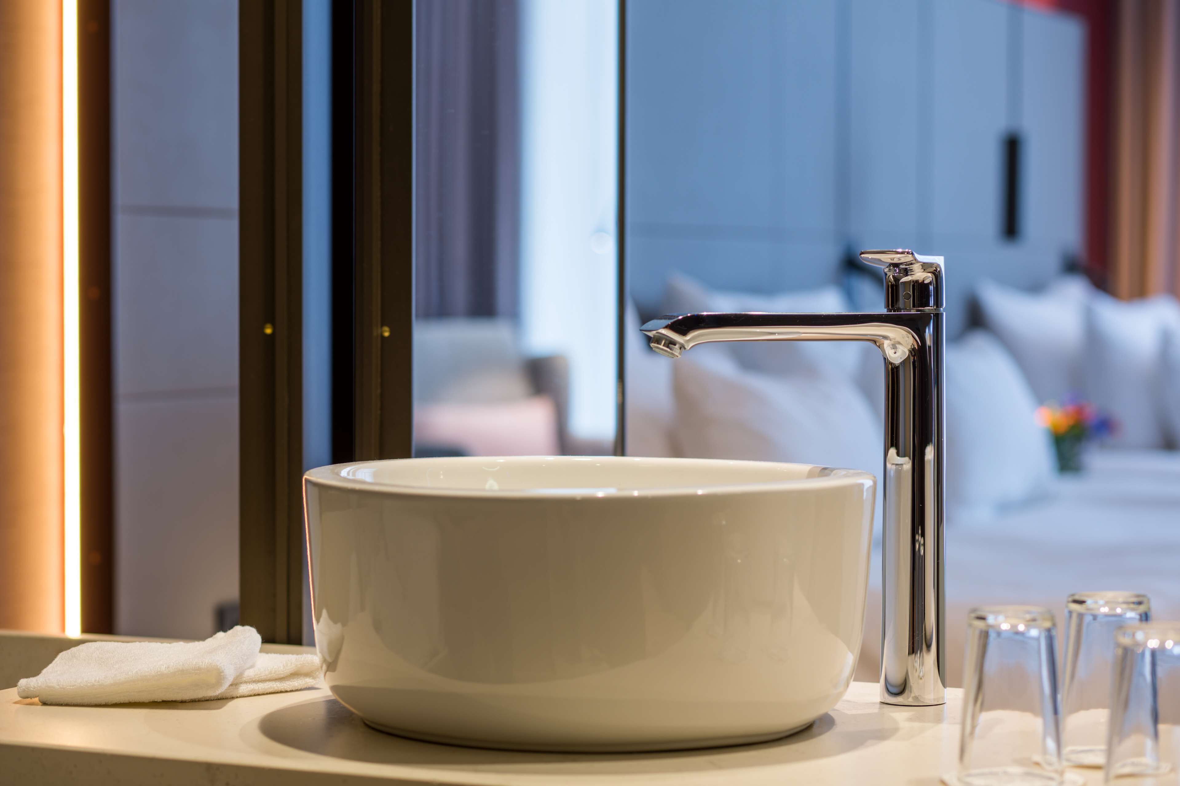 Un lavabo de cerámica blanca con un grifo de cromo en un baño de hotel.
