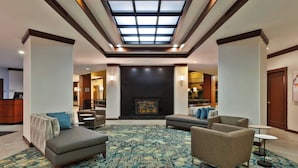 A spacious lobby with a high ceiling, a fireplace, and comfortable seating areas. - Hotel Auburn Hills (Auburn Hills)