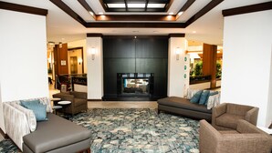 A spacious lobby with a patterned carpet, sofas, and a fireplace. - Hotel Auburn Hills (Auburn Hills)