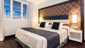 A hotel room with a large bed, two bedside tables, a nightstand, and a window with curtains. - Hotel Gran Versalles (Madrid)