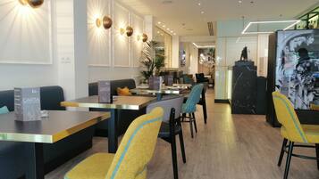 Un moderno vestíbulo de hotel con zonas de estar, mesas y una recepción.