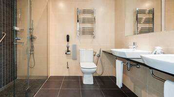 Een moderne badkamer met een douche met glazen wand, een toilet en een wastafel met een handdoekhouder.