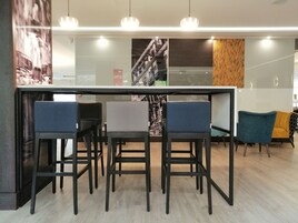 Un espace bar moderne avec une cloison en verre, quatre tabourets de bar et un mélange de décor contemporain et classique.