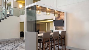 A modern conference room with a glass partition, a flat-screen TV, and a long table with chairs.