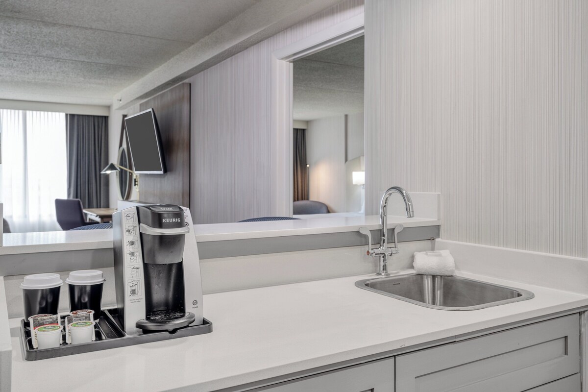 Une chambre d’hôtel moderne dotée d’une kitchenette, comprenant une machine à café, un évier et un plan de travail.