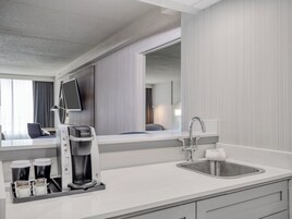 Una habitación de hotel moderna con cafetera, lavamanos y espejo.
