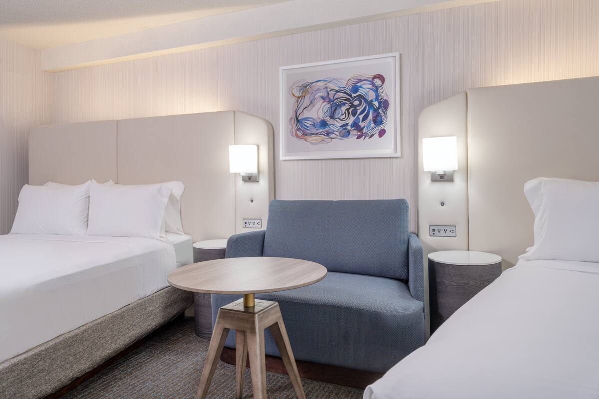 Ein Hotelzimmer mit einem Bett, einem Sofa, einem kleinen runden Tisch und zwei Nachttischlampen.
