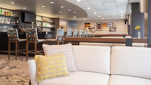 A modern bar area with seating and a television screen.