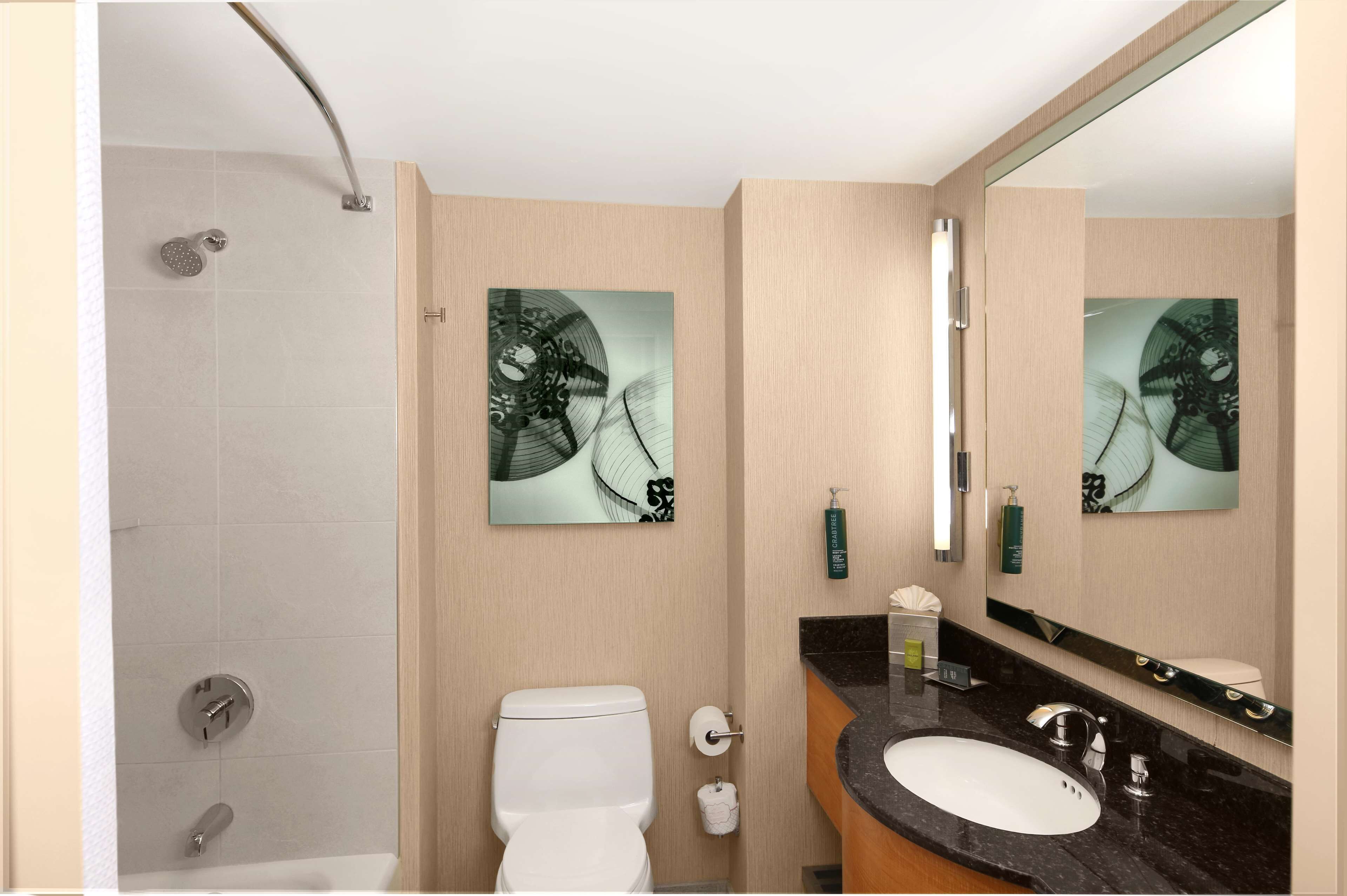A modern bathroom with a shower, toilet, sink, and large mirror.