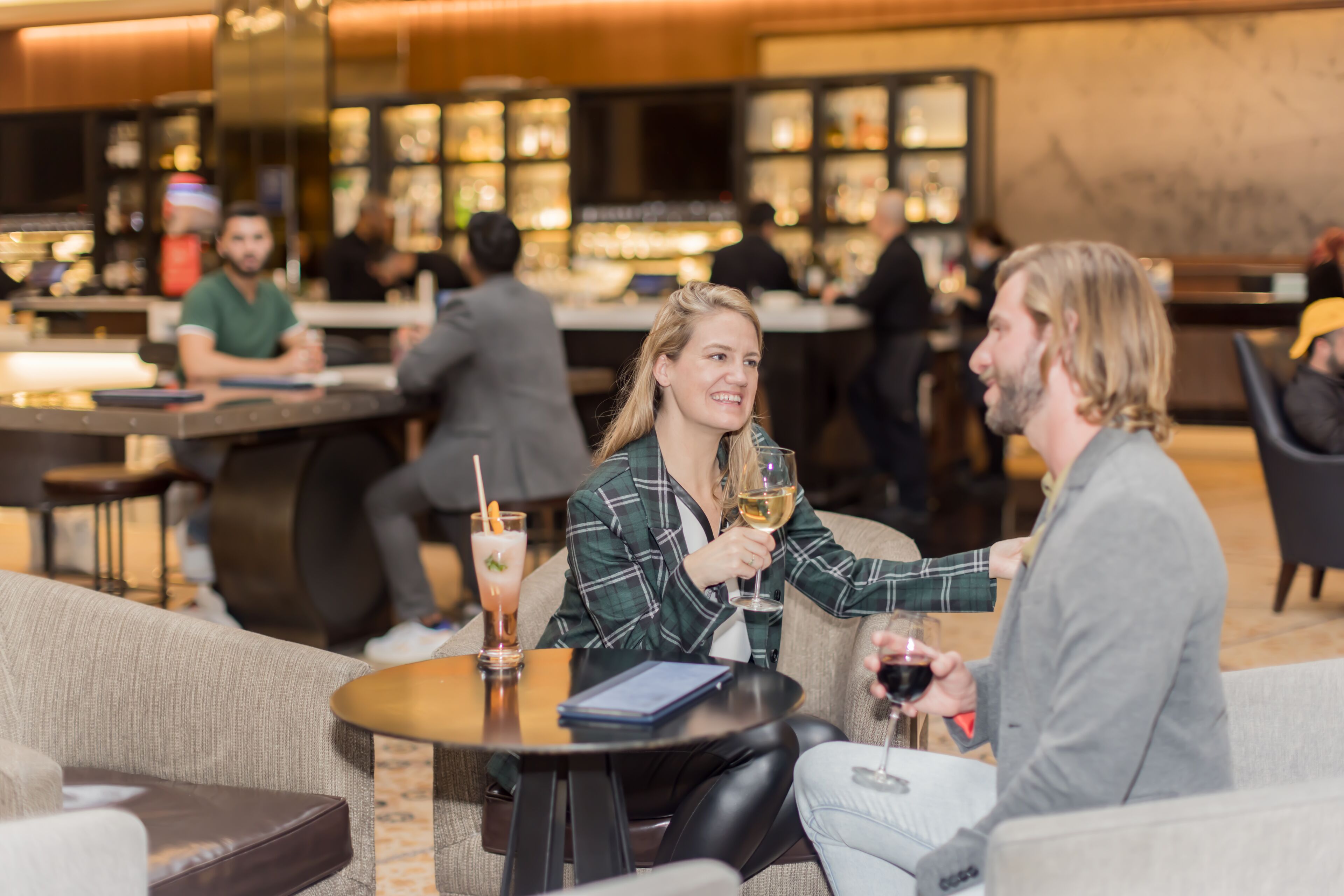 Un espace bar avec des tables et des chaises, un comptoir, et des personnes assises et debout.