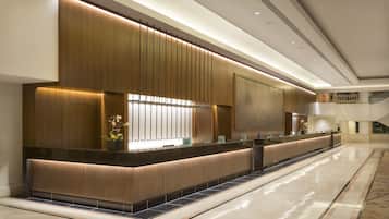 Un área de recepción moderna con una larga recepción, paneles de madera y piso de baldosas.
