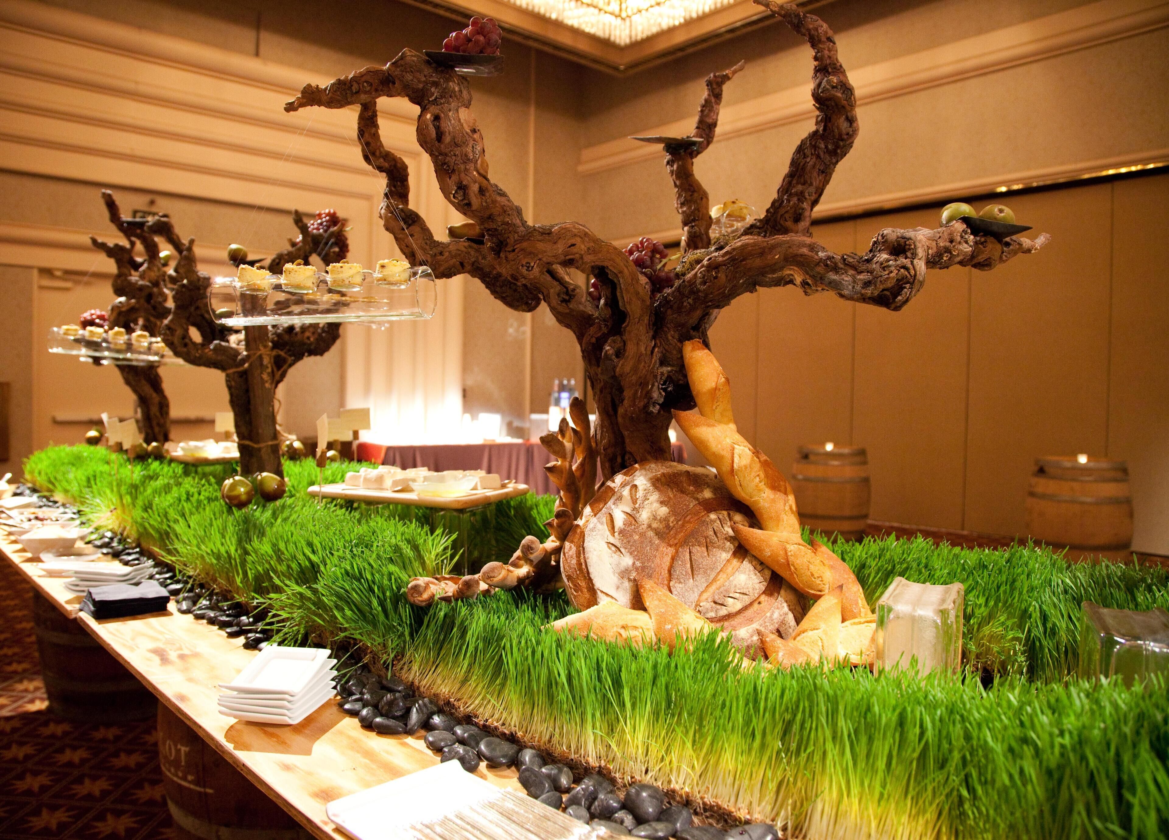 A long buffet table with a rustic centerpiece featuring a tree-like structure supporting various food items.