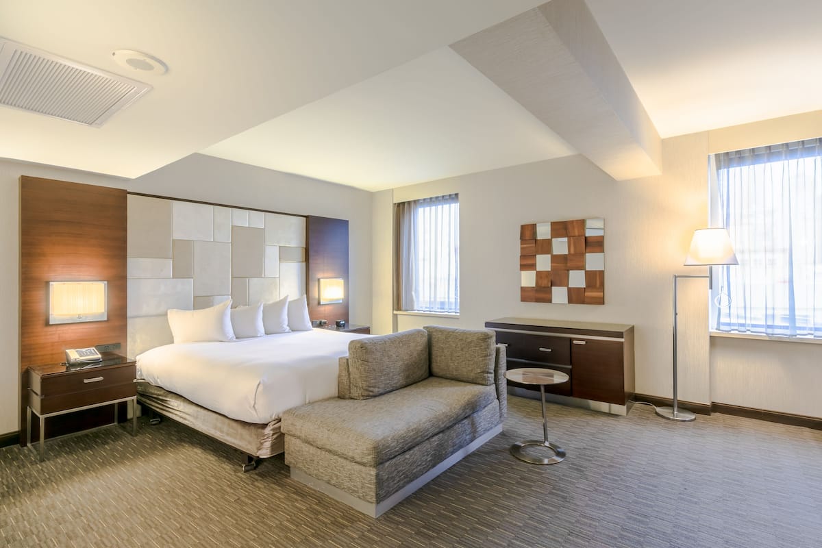 Habitación de hotel con una cama grande, un sofá, un escritorio y una lámpara.