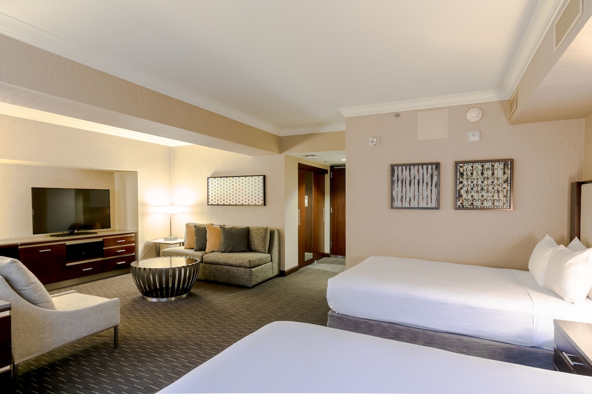A hotel room with a bed, a sofa, a TV, and a desk.
