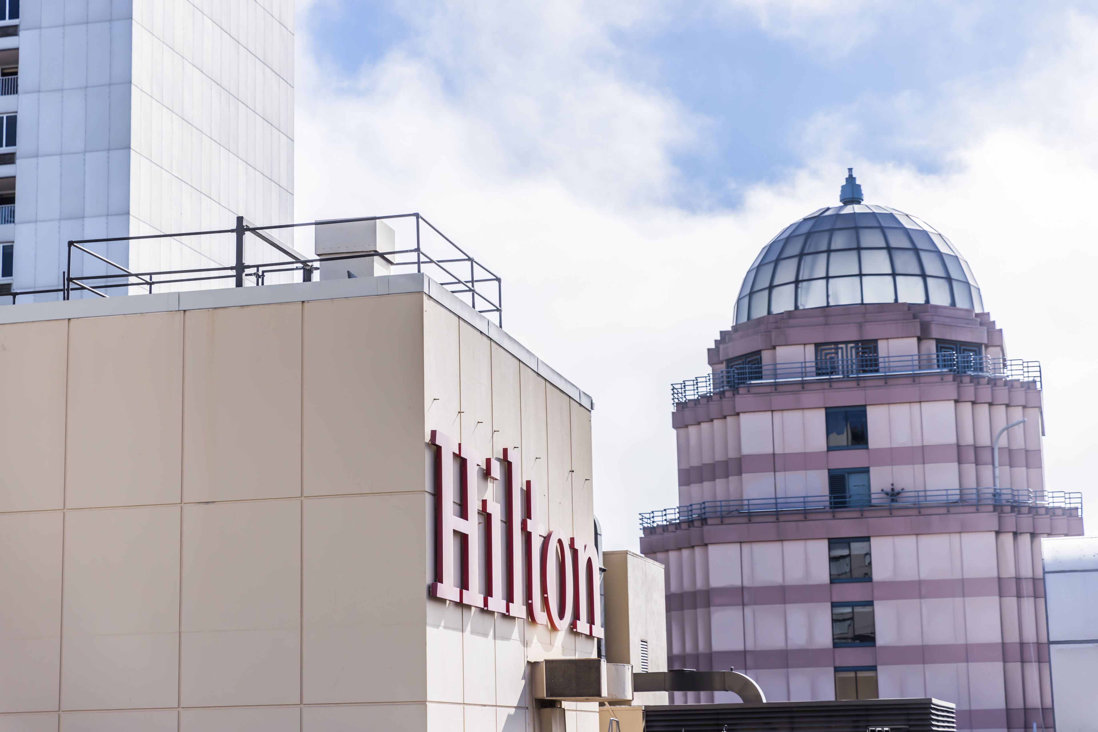 A hotel with a prominent 'Hilton' sign, a modern building with a dome structure, and a large glass window.