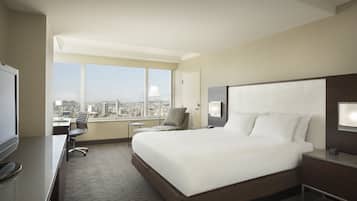 A hotel room with a large bed, a desk, a chair, and a TV.