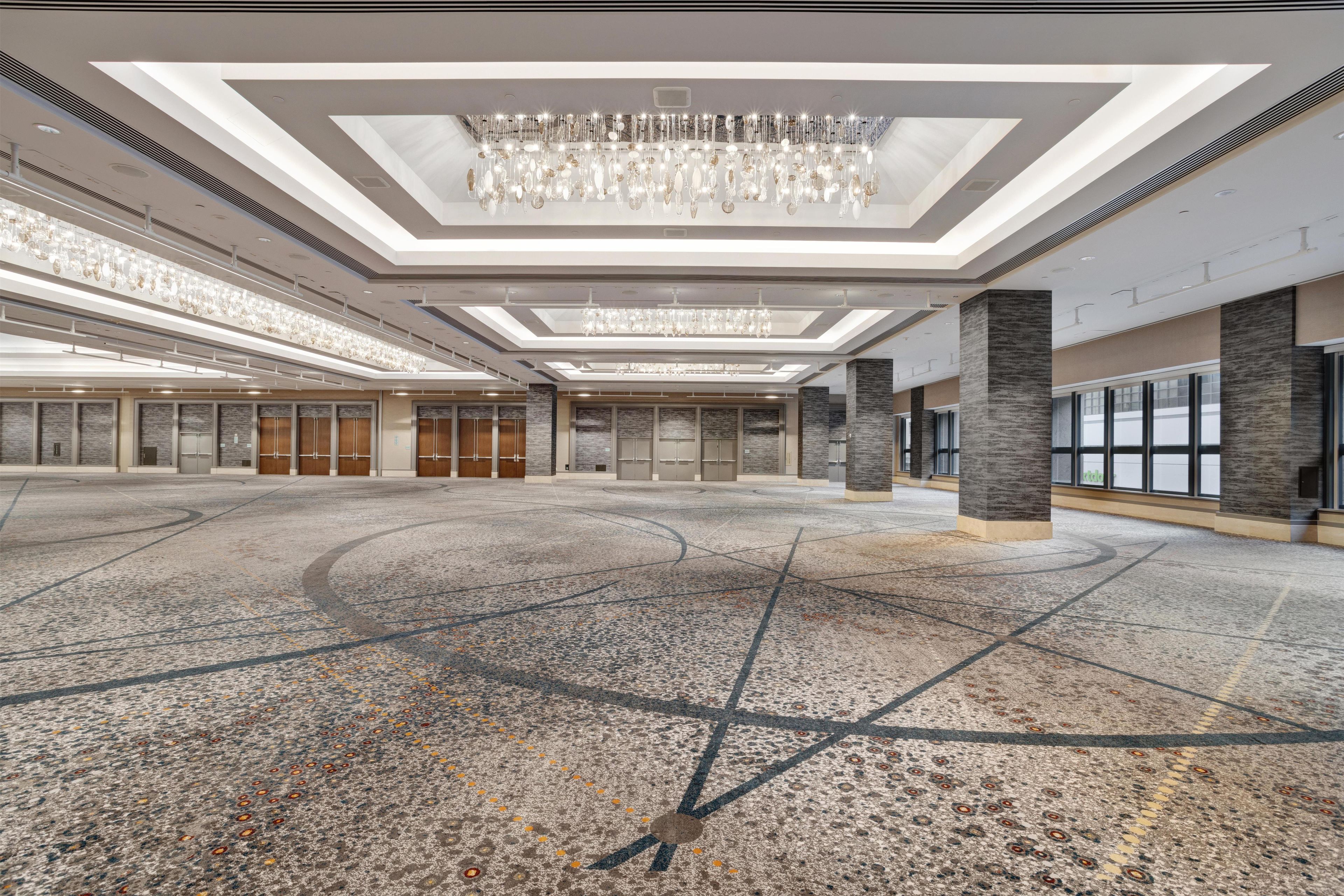 A spacious indoor area with a high ceiling, multiple doors, and a patterned floor.