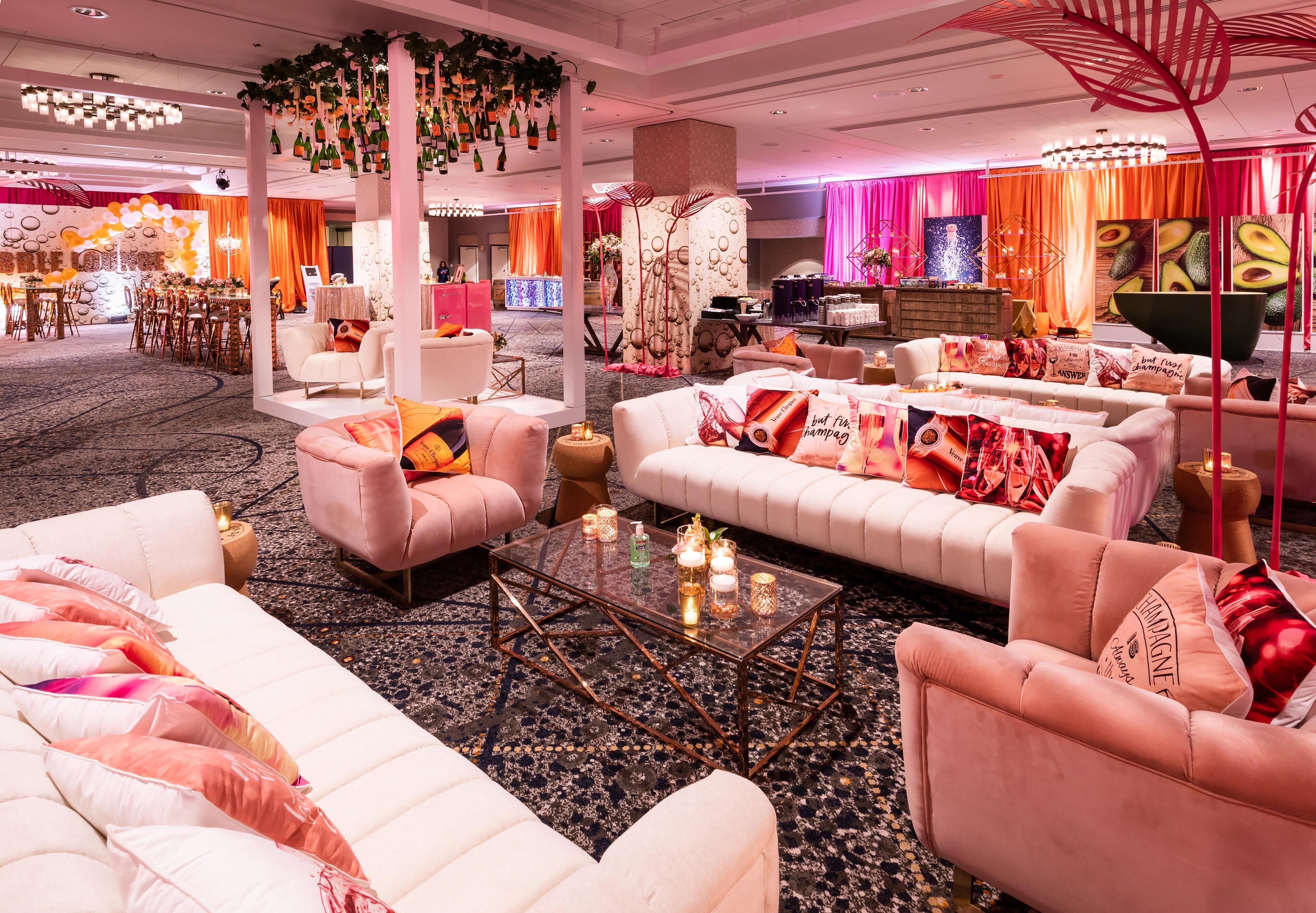 A spacious lounge area with plush seating, a central coffee table, and decorative elements like hanging bottles and a unique red sculpture.