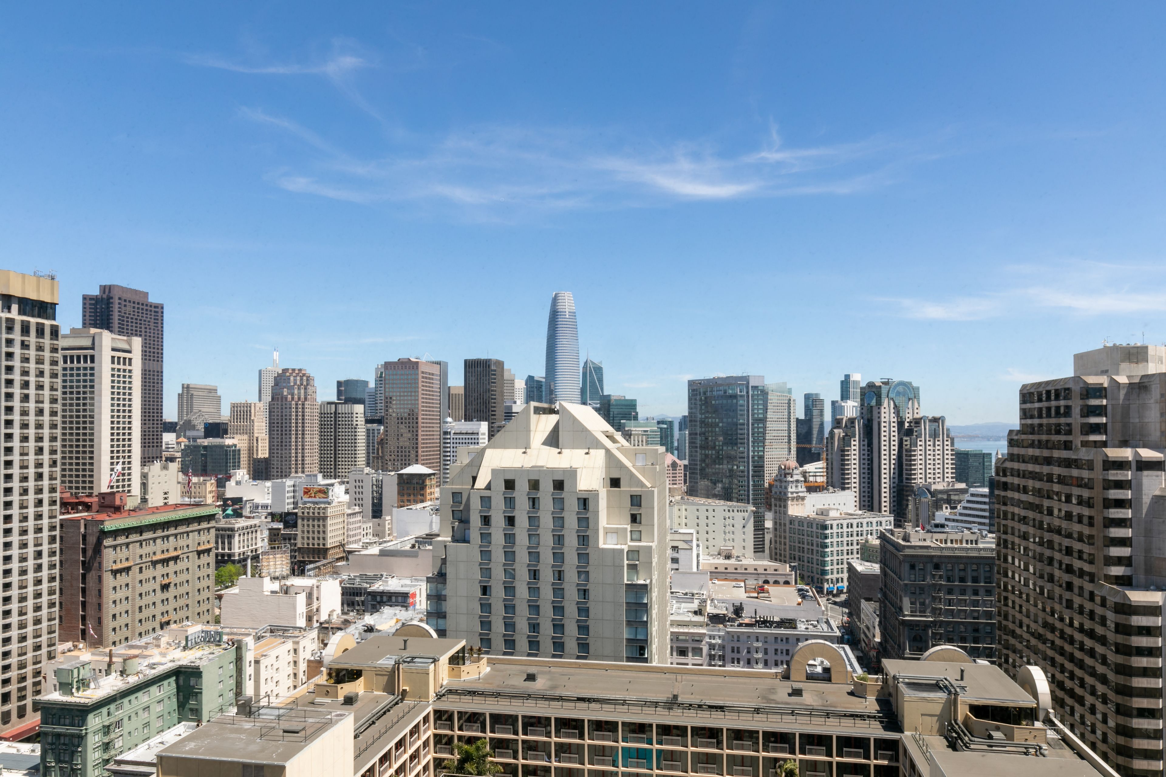 A cityscape with a prominent modern skyscraper in the center, surrounded by various buildings.