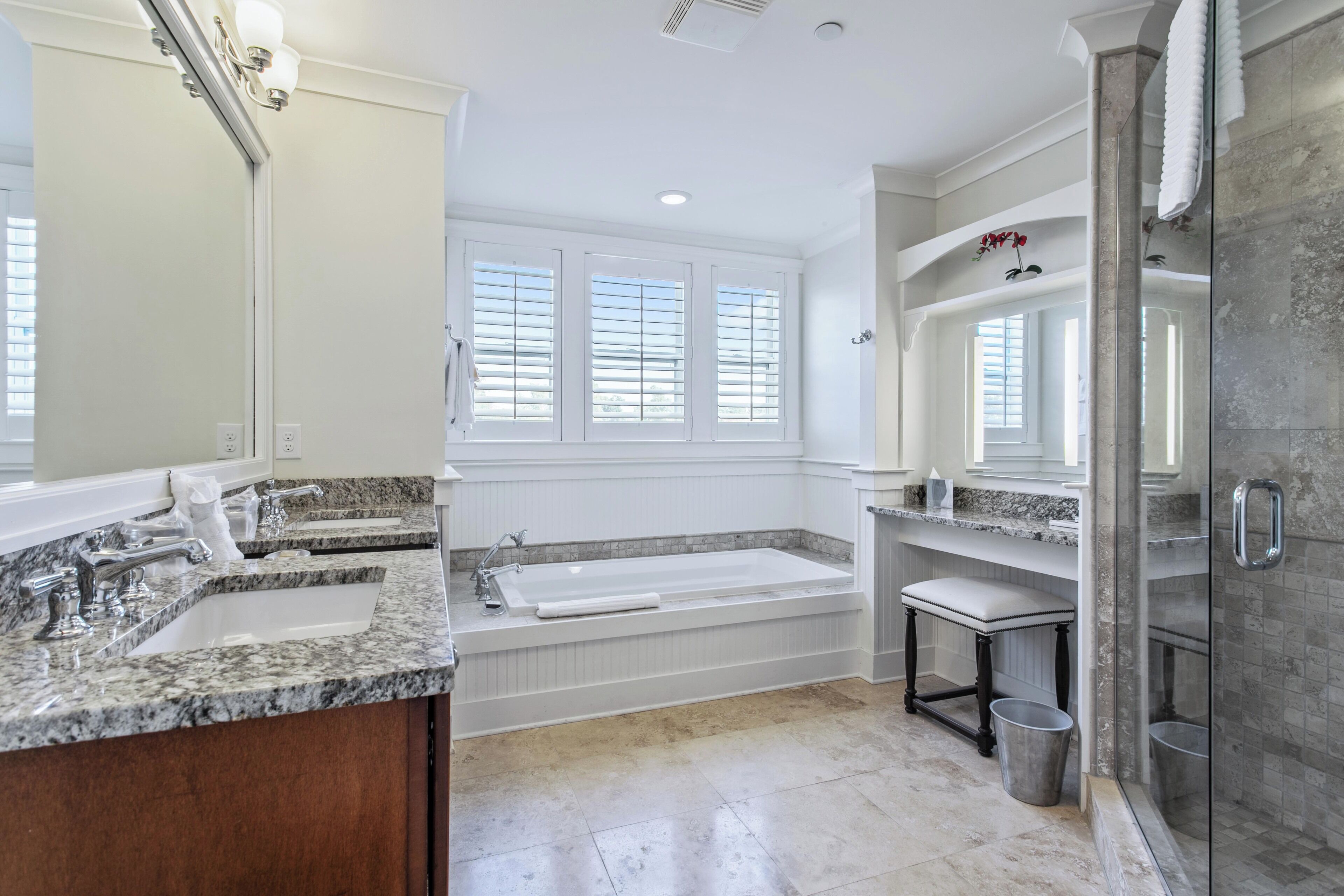 A modern bathroom with a large bathtub, a double sink vanity, and a glass-enclosed shower area.