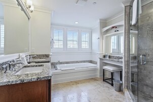 Un baño moderno con una bañera grande, un tocador doble y una zona de ducha con paredes de vidrio.