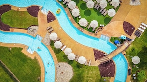 Vista aérea de un resort con una gran piscina, un tobogán acuático y varias zonas de descanso con sombrillas.