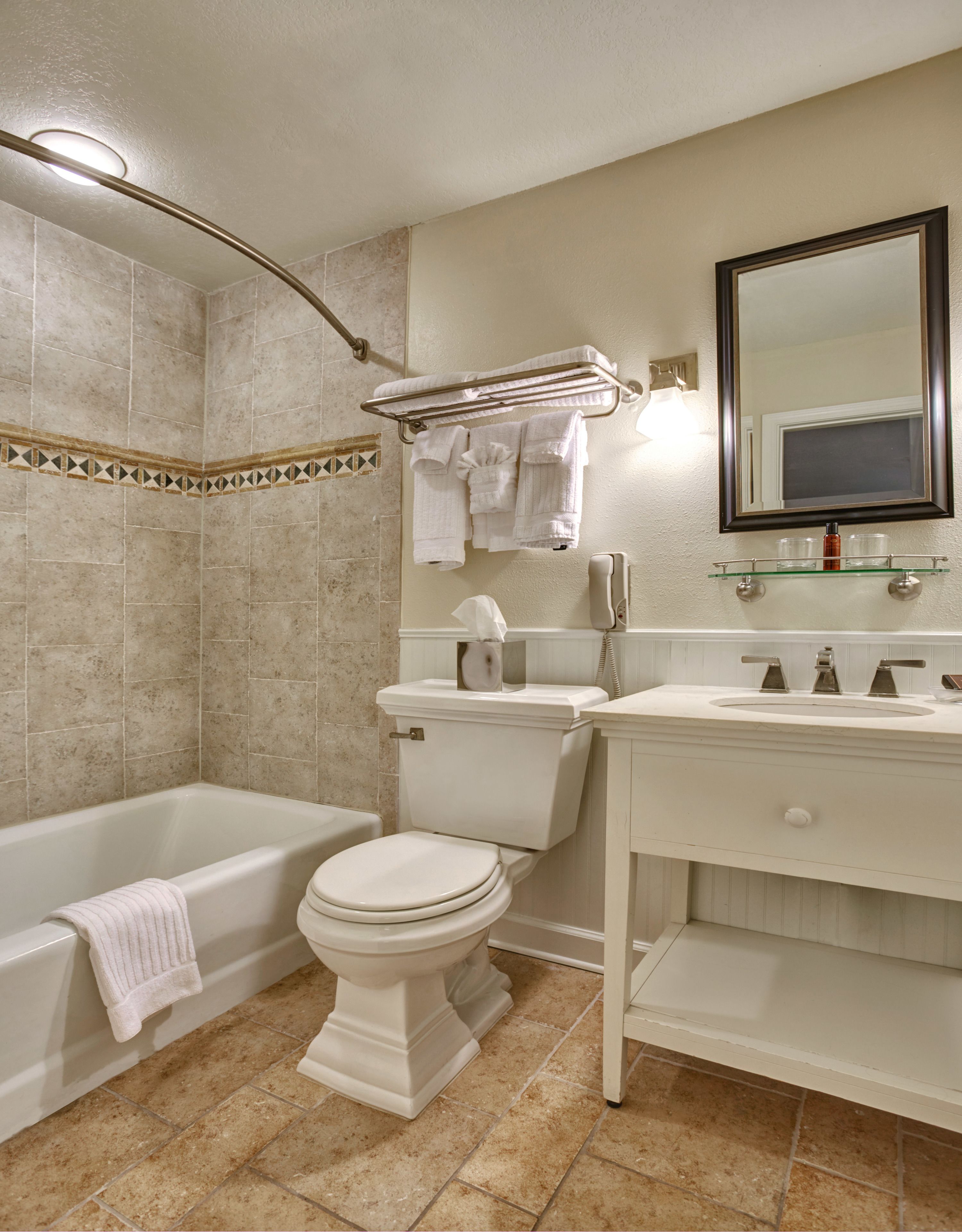 A bathroom with a bathtub, toilet, and vanity with a mirror.