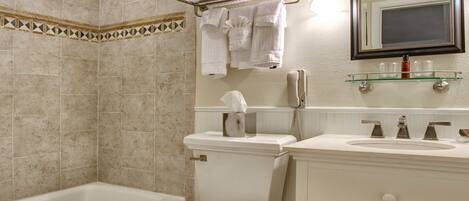 A bathroom with a bathtub, toilet, and vanity with a mirror.