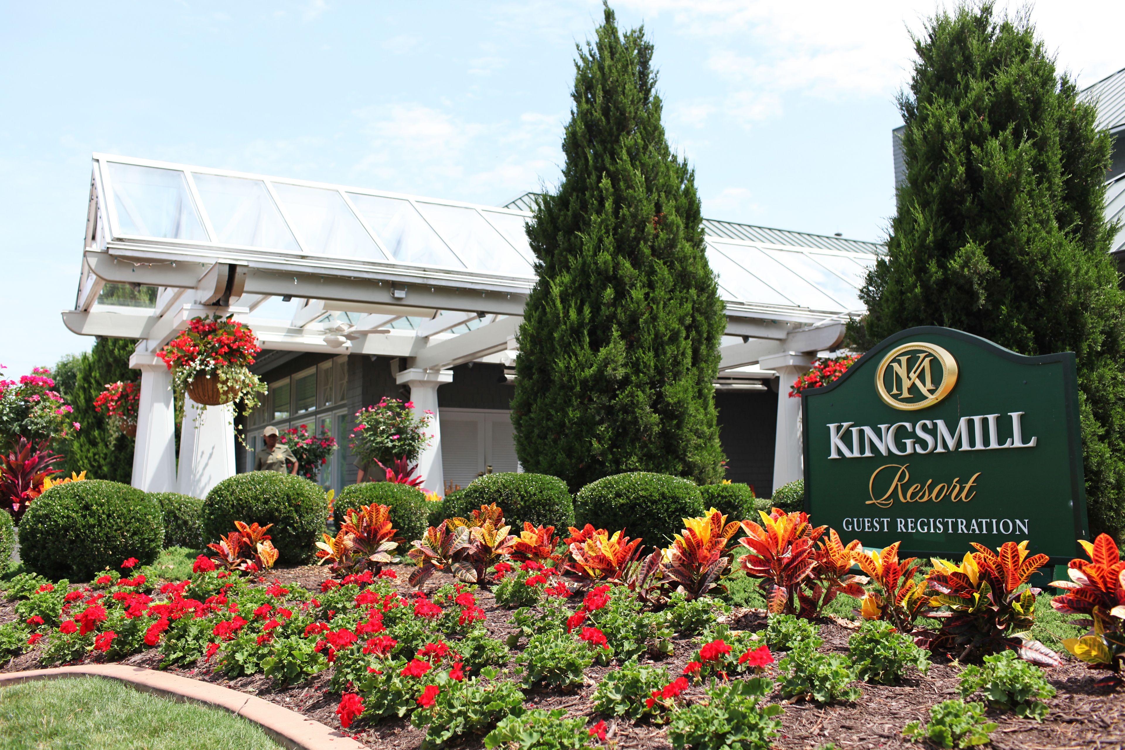 A Kingsmill Resort sign with a guest registration area, surrounded by well-maintained flower beds and a modern building structure.