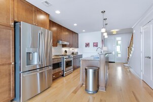Una cocina moderna con electrodomésticos de acero inoxidable, armarios de madera y una isla central.