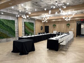 Un salón de conferencias con mesas largas, sillas y una lámpara de araña moderna.