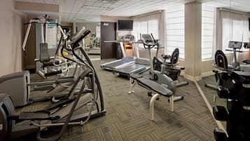 Un gimnasio con diversos equipos de ejercicio, incluyendo cintas de correr, elípticas y pesas libres.