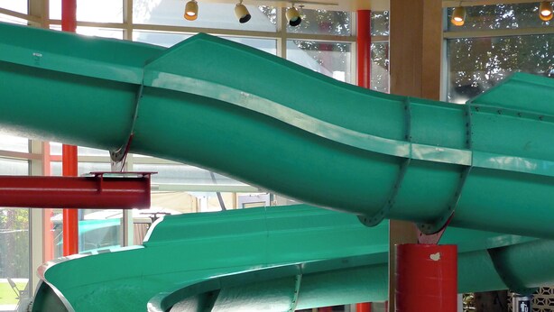 Un tobogán de agua grande en el interior con una piscina al final.
