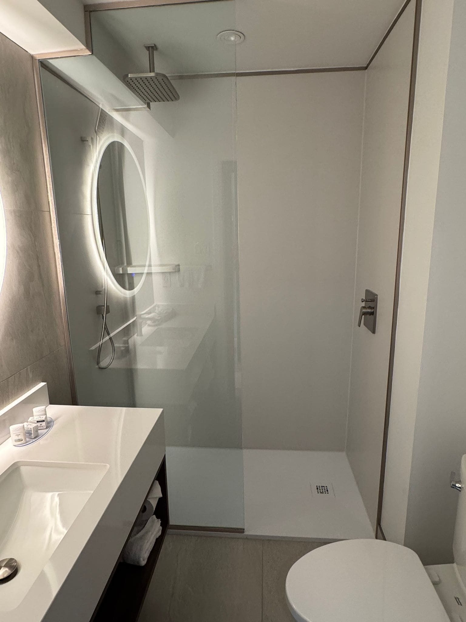 A modern bathroom with a glass-enclosed shower, a vanity with a mirror, and a toilet.