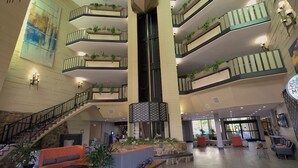 A multi-level atrium with a central staircase, balconies with plants, and seating areas.