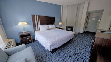 A hotel room with a large bed, two bedside tables with lamps, a sofa, and a carpeted floor.