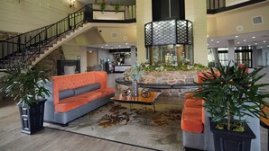 A spacious lobby with a staircase, a sofa, a coffee table, and potted plants.