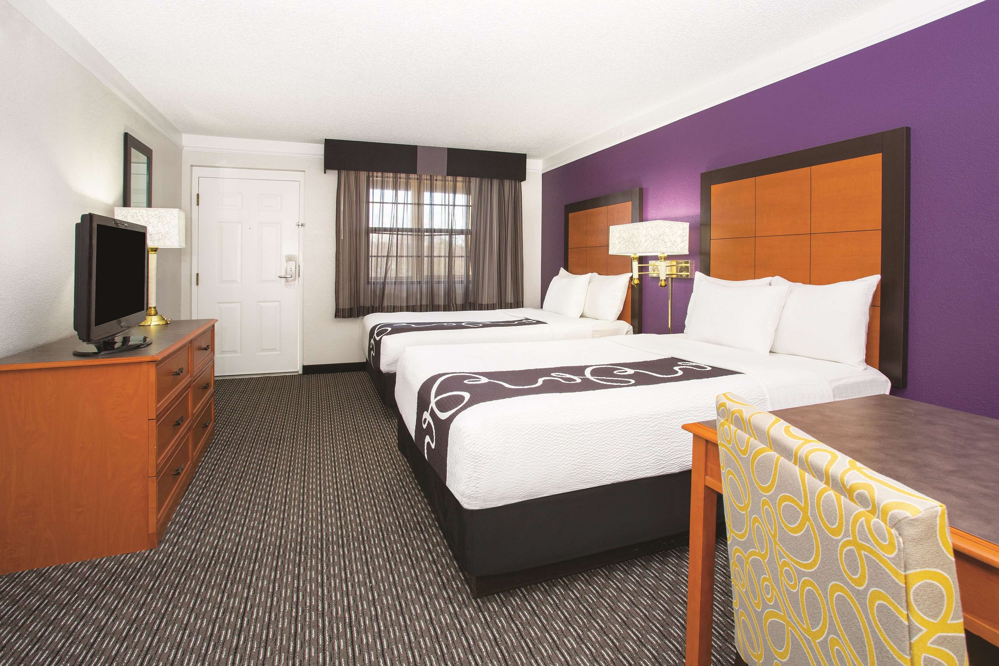 A hotel room with two beds, a TV, a desk, and a chair.