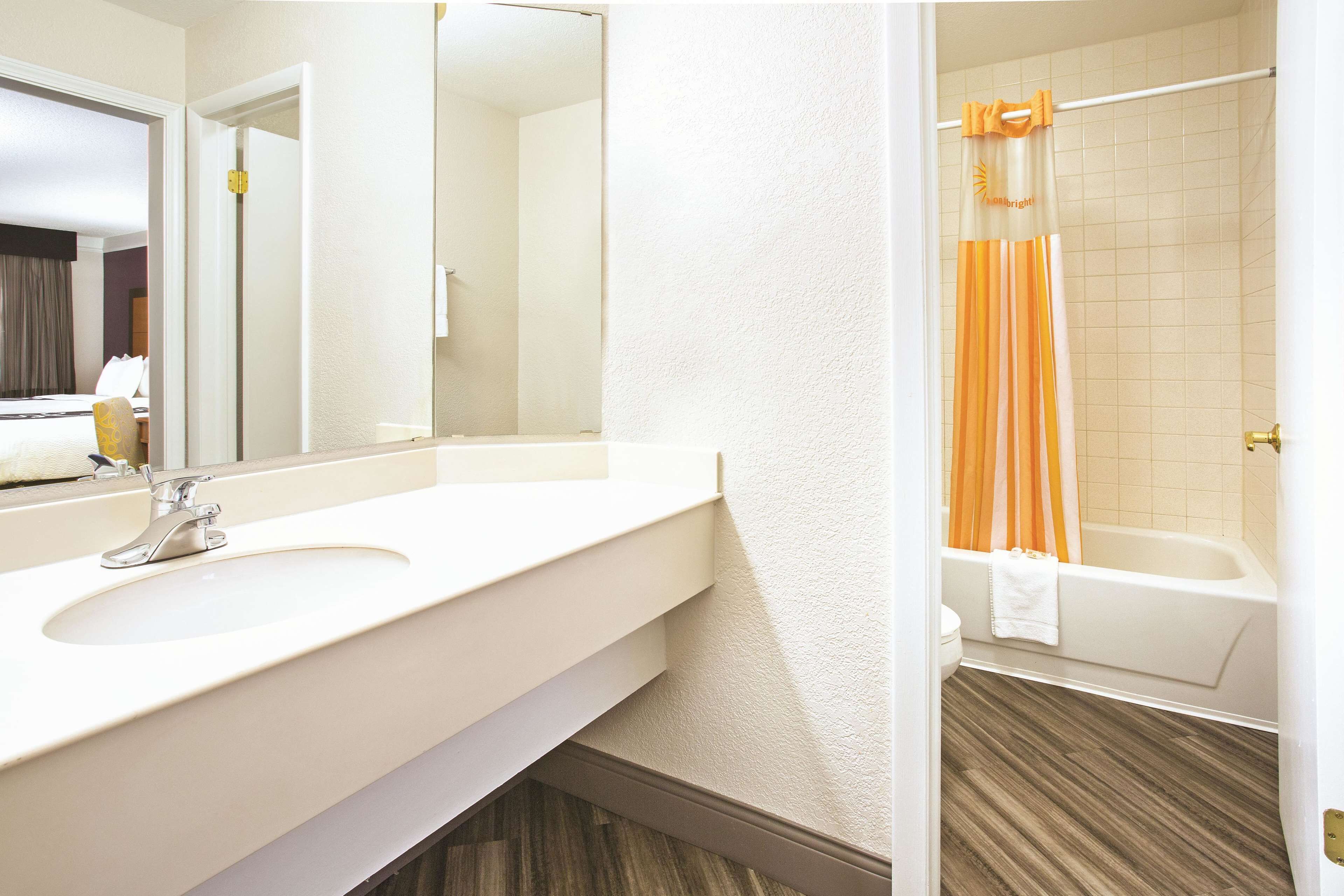 Une salle de bain avec un lavabo blanc, un miroir et une baignoire.