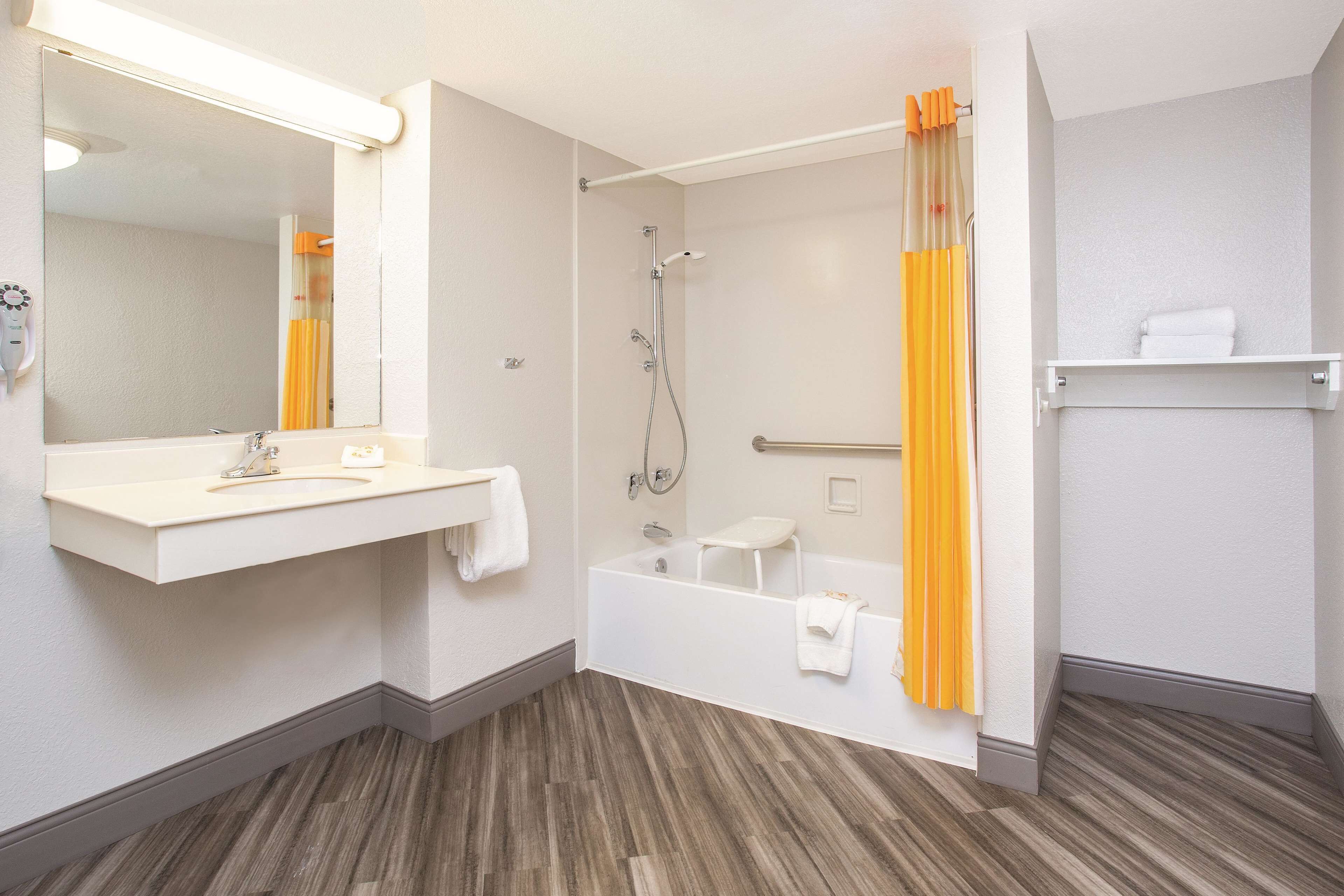 A bathroom with a sink, mirror, shower, and bathtub.