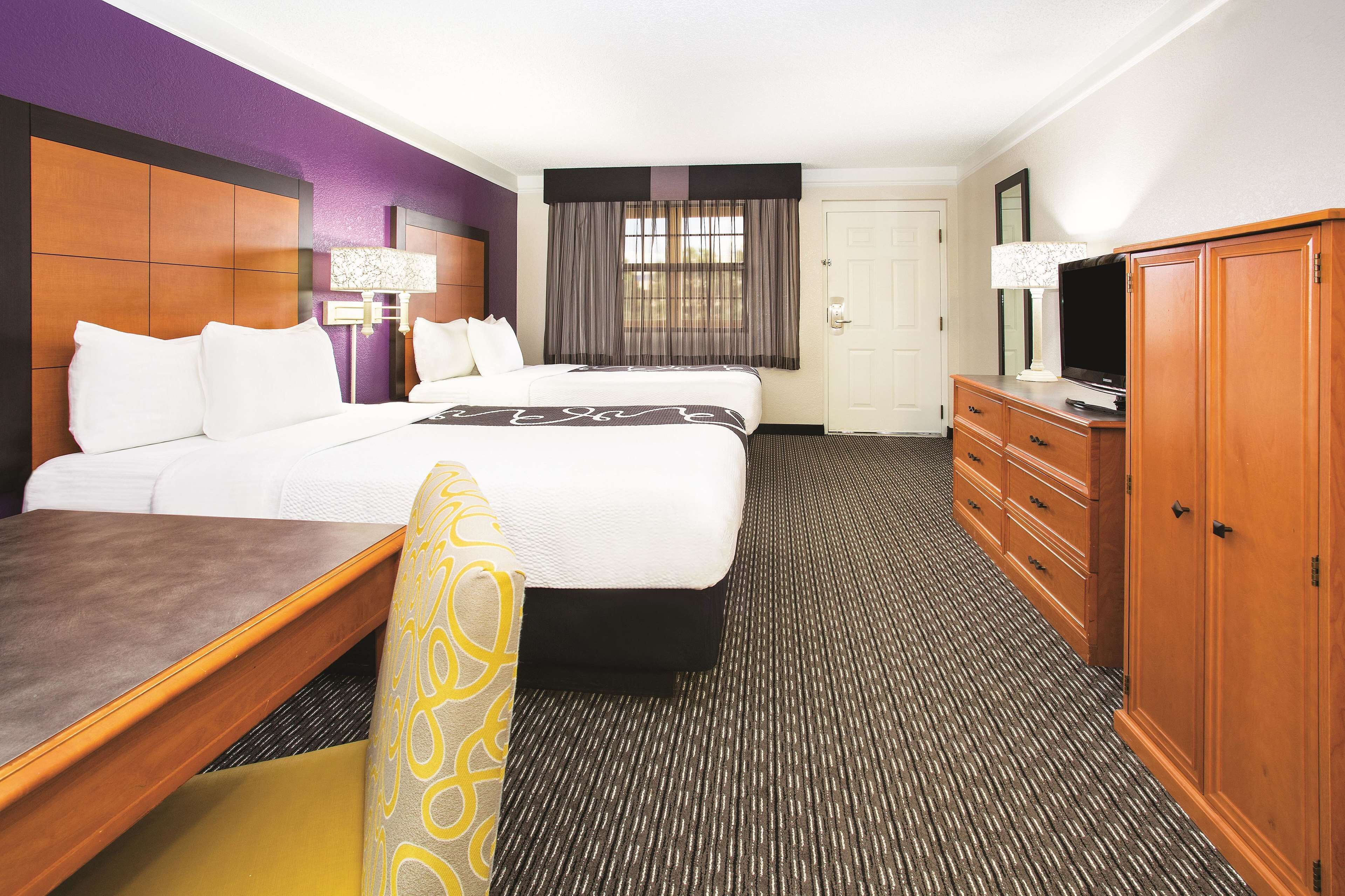 Una habitación de hotel con cama, escritorio, televisión y armario.