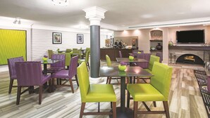 A dining area with green and purple chairs, a fireplace, and a flat-screen TV on the wall. - La Quinta Inn by Wyndham Denver Westminster (Westminster)