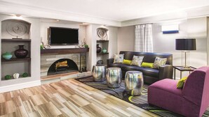 A modern living room with a fireplace, a flat-screen TV, a sofa, and decorative items. - La Quinta Inn by Wyndham Denver Westminster (Westminster)