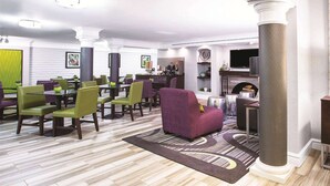 A spacious lobby with a fireplace, seating area with green and purple chairs, and a modern design. - La Quinta Inn by Wyndham Denver Westminster (Westminster)