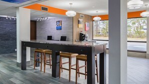 A modern reception area with a bar, seating, and a view of the outdoors. - Motel 6 Savannah, GA - Midtown (Savannah)