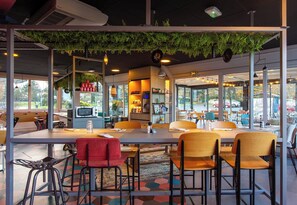Un comedor interior con una mesa larga, varias sillas y una zona de bar con taburetes.