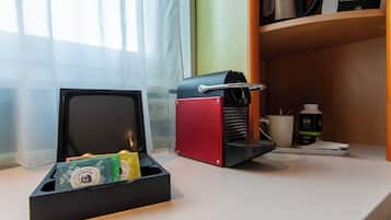 Un área de cocina con una cafetera, una caja de bolsitas de té y una máquina para hacer café en la encimera.