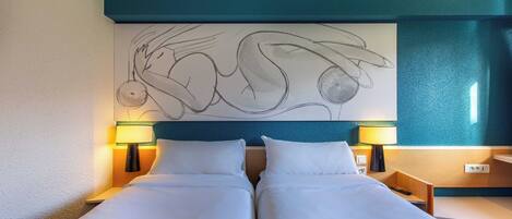 Une chambre d’hôtel avec un grand lit, deux tables de chevet, deux lampes et une œuvre d’art murale.