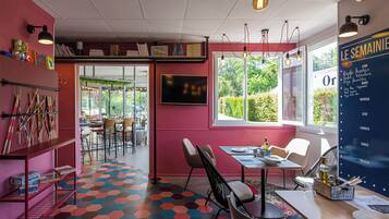 Um interior moderno com um vibrante padrão hexagonal no chão, uma área de jantar com mesa e cadeiras, e uma grande janela com vista para o verde.